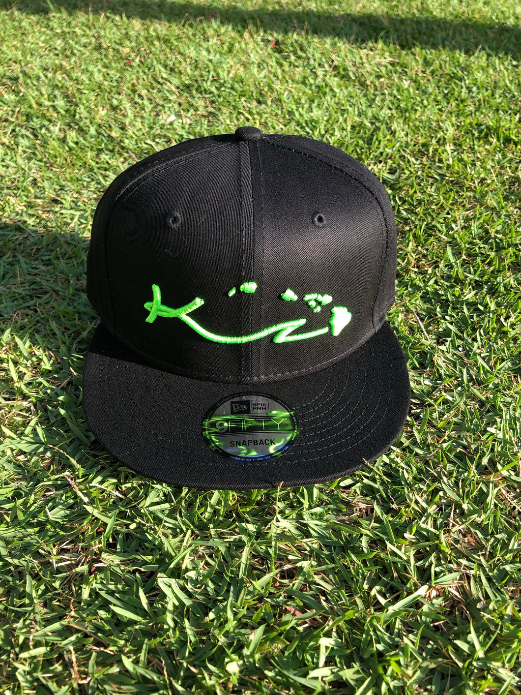 BLACK SNAP BACK HAT WITH FLUORESCENT GREEN LOGO AND ISLANDS